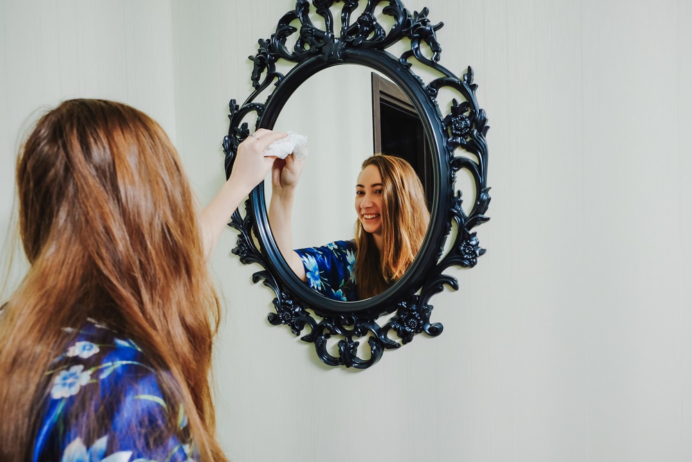 professional housecleaner cleaning a mirror